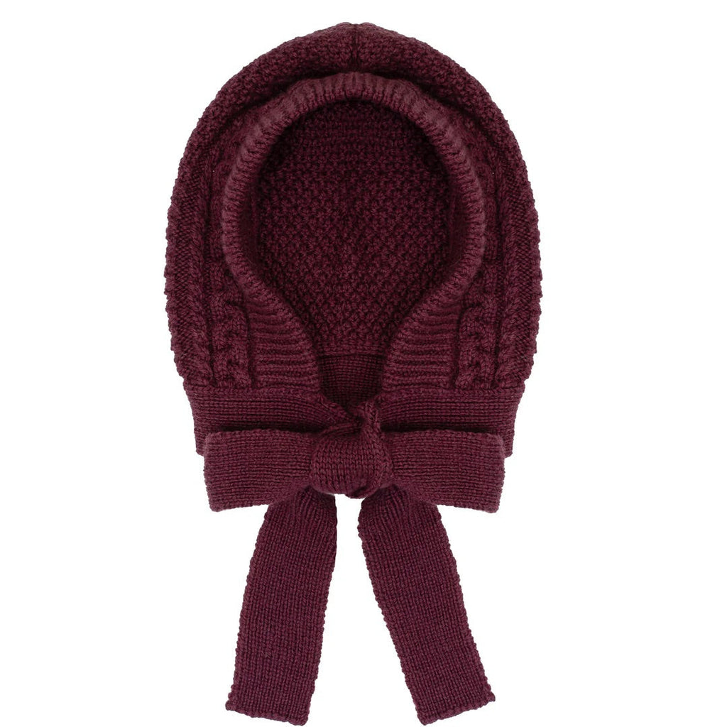 Knitted burgundy baby bonnet with a bow on a white background